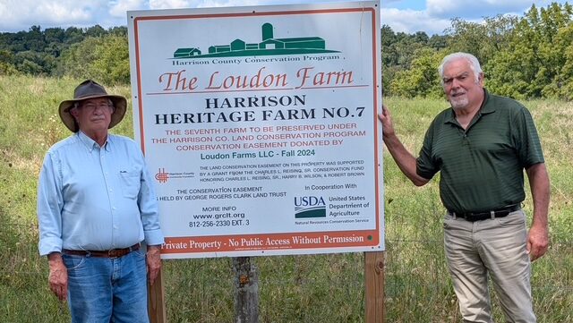 Two men stand in front of a sign saying 'The Loudon Farm"